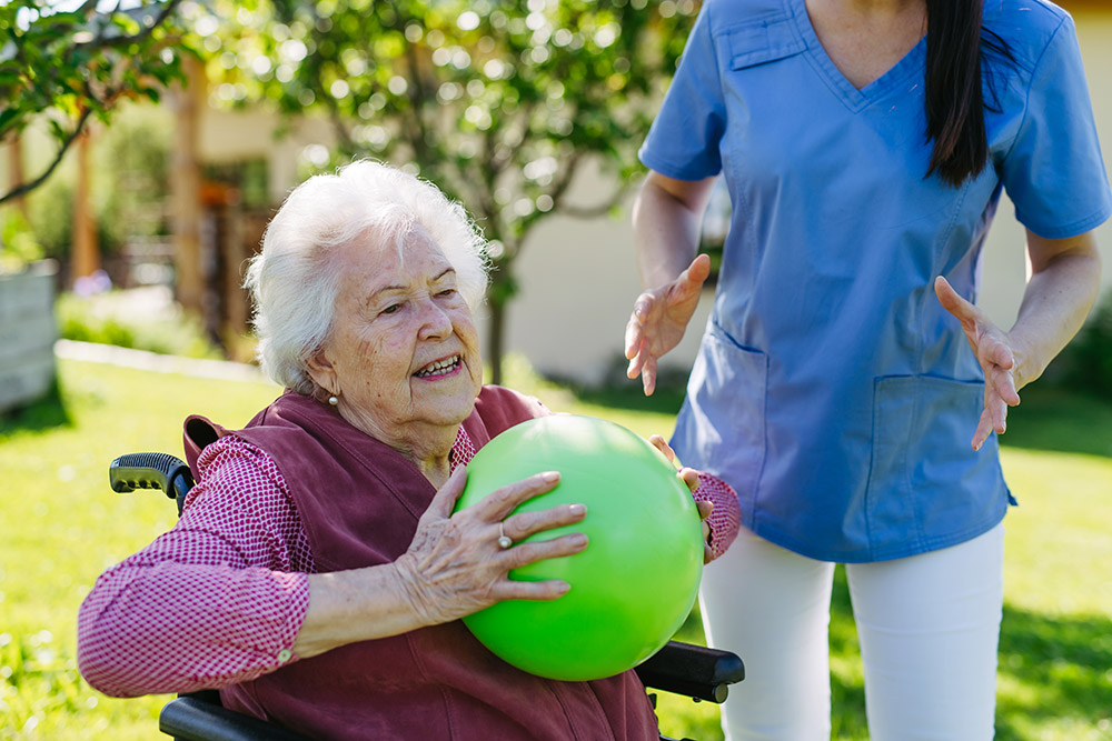 elderly woman using ball for rehab